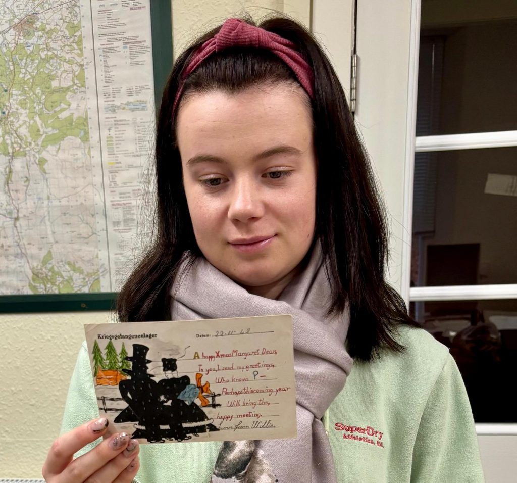 Collections Assistant Lucy Looking at a World War Two, Prisoner of War Postcard